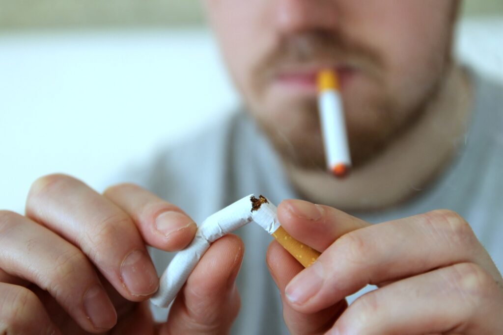 A discarded cigarette pack beside an e-cigarette on a bright desk